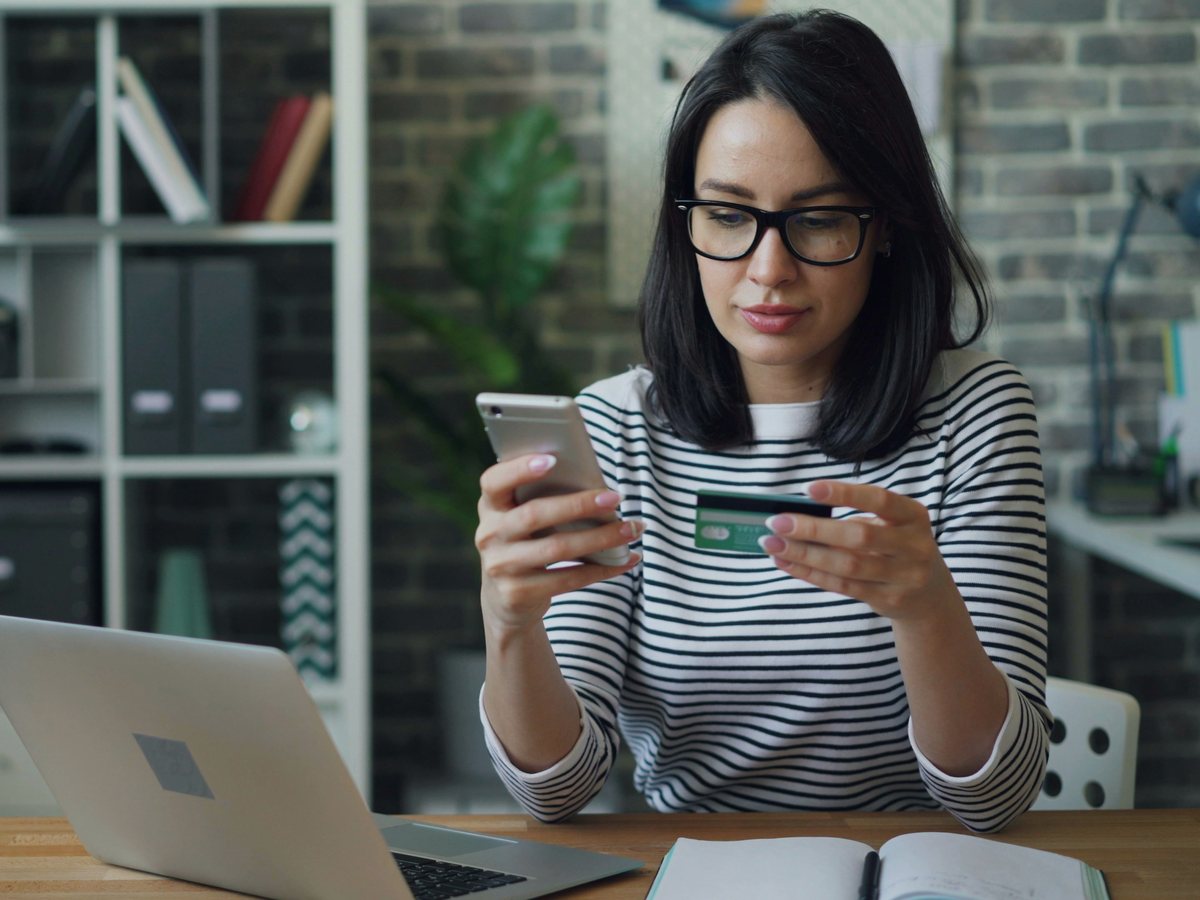 A person at a desk checking a payment on their phone.