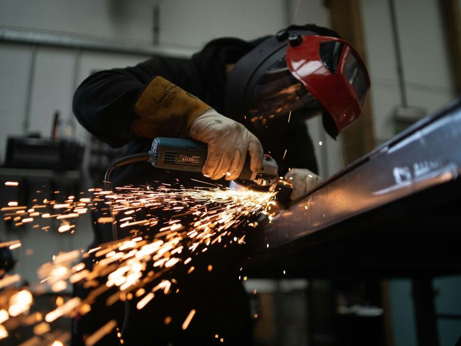 A fabricator grinding steel in a workshop.