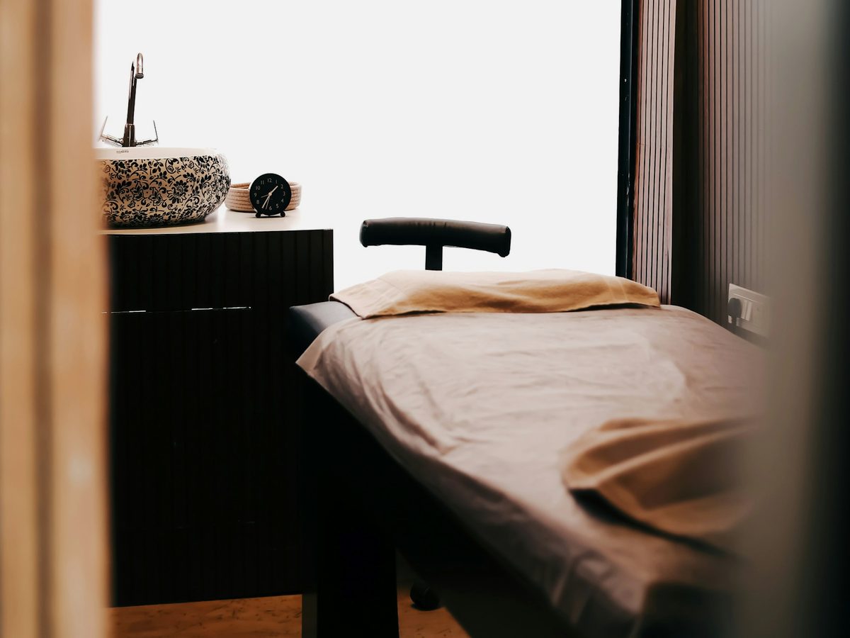 A treatment room with a couch and a basin.
